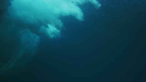 vista lateral bajo el agua de las olas del océano que se rompen con niebla y pulverización