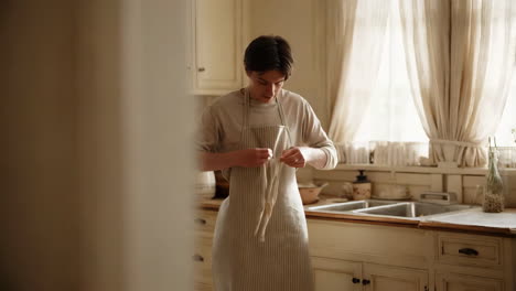person adjusting apron in a sunny rustic kitchen