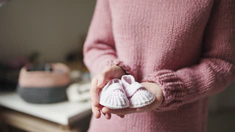 baby booties on female palms. knitted shoes handmade for children