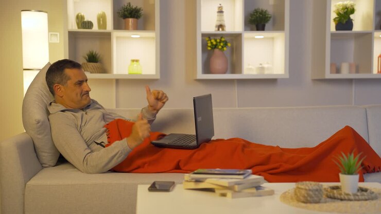 Happy man using laptop lying down.
