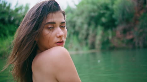 retrato de una hermosa mujer desnuda mirando a la cámara en el lago.