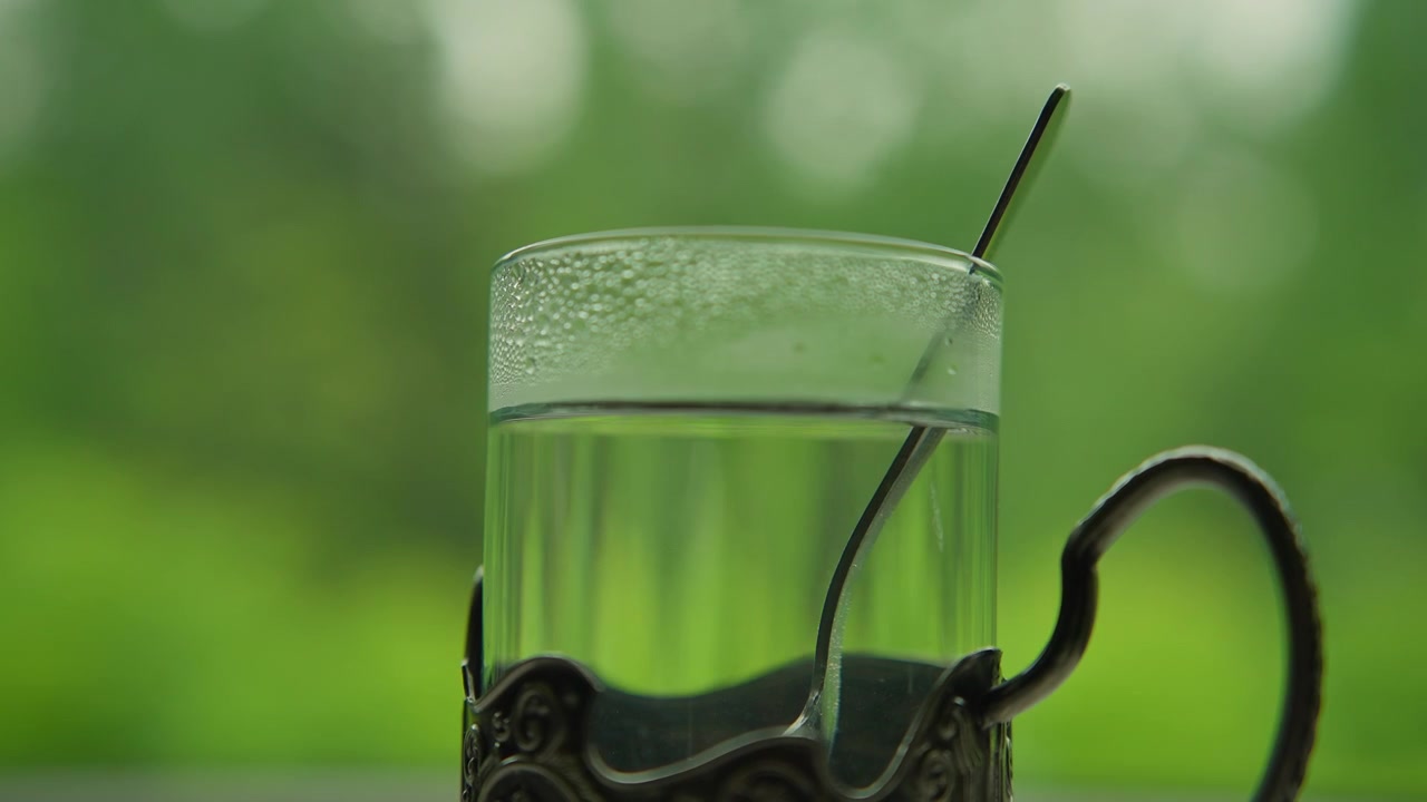Bevanda rinfrescante in un bicchiere di vetro con supporto in metallo e sfondo verde