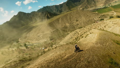 extreme lover rides motorbike along hill ridge fpv drone. motorcyclist on vehicle competes for victory in offroad racing at highland. extreme hobby