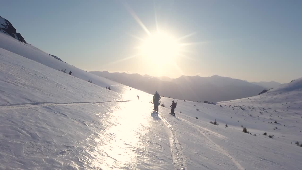 dolly siguiendo a dos hombres esquiando a través de la colina cubierta de nieve piltriquitron al atardecer, el bolsón, patagonia argentina