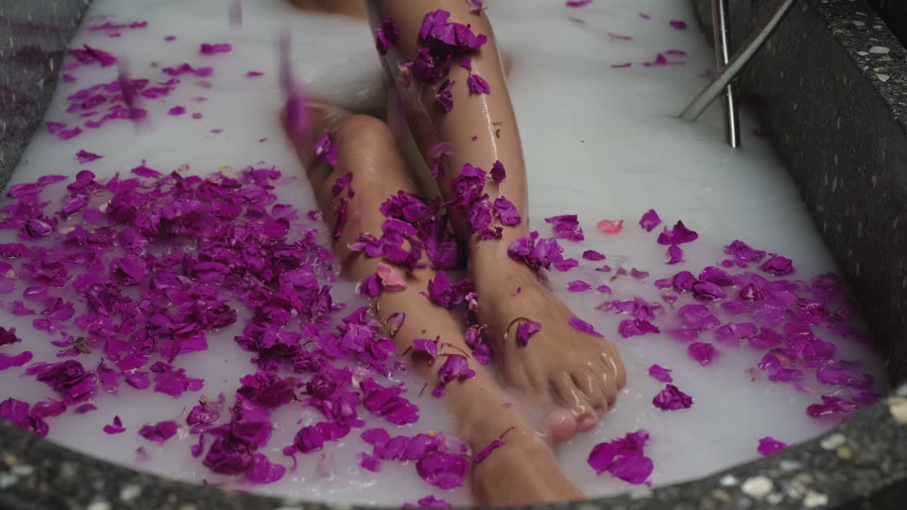 Woman enjoying a milk bath with purple flowers