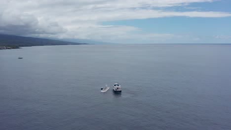 close-up panning shot of a ferry approaching a submarine in the open water off the coast of kailua-kona on the big island of hawai'i