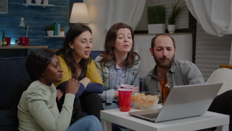 multiethnic friends sitting on couch having online videocall meeting