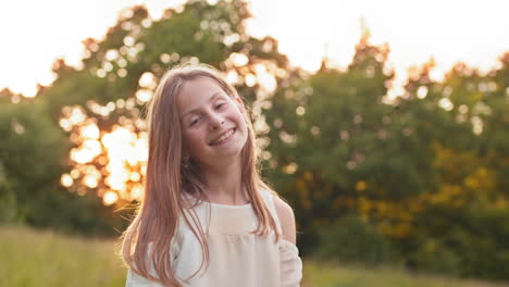 smiling girl in a field at sunset