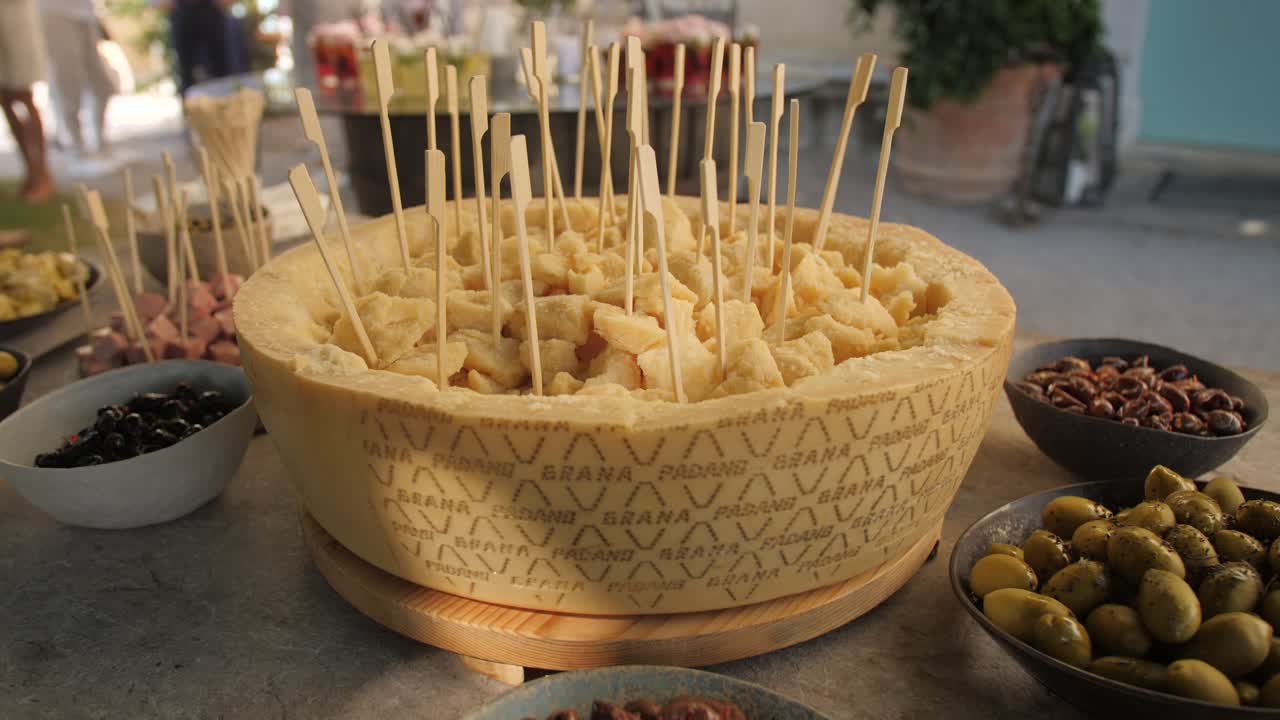rueda de queso grana padano en la mesa lista para que los invitados coman con tenedores de madera
