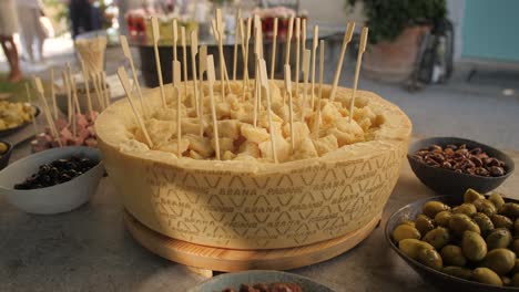 Grana-Padano-Käselaib-Auf-Dem-Tisch,-Bereit-Für-Die-Gäste,-Mit-Holzgabeln-Zu-Essen