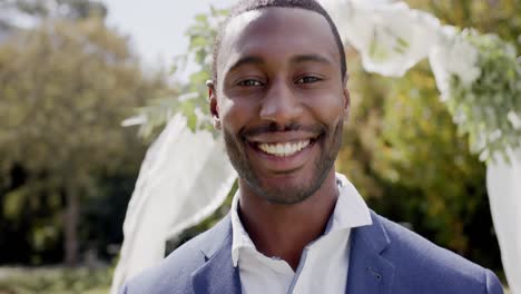 Portrait-of-happy-african-american-groom-smiling-at-wedding-ceremony-in-sunny-garden,-in-slow-motion