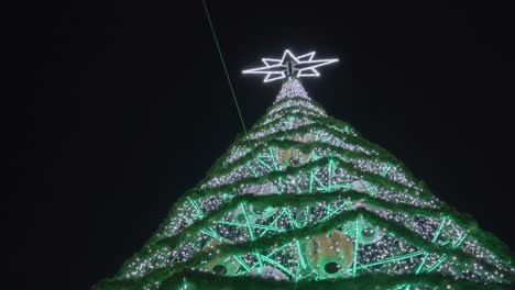 Ein-Hoher,-Heller-Weihnachtsbaum-Mit-Einem-Großen-Stern-An-Der-Spitze,-Der-Die-Stadt-Im-Dezember-Beleuchtet---Weitwinkelaufnahme