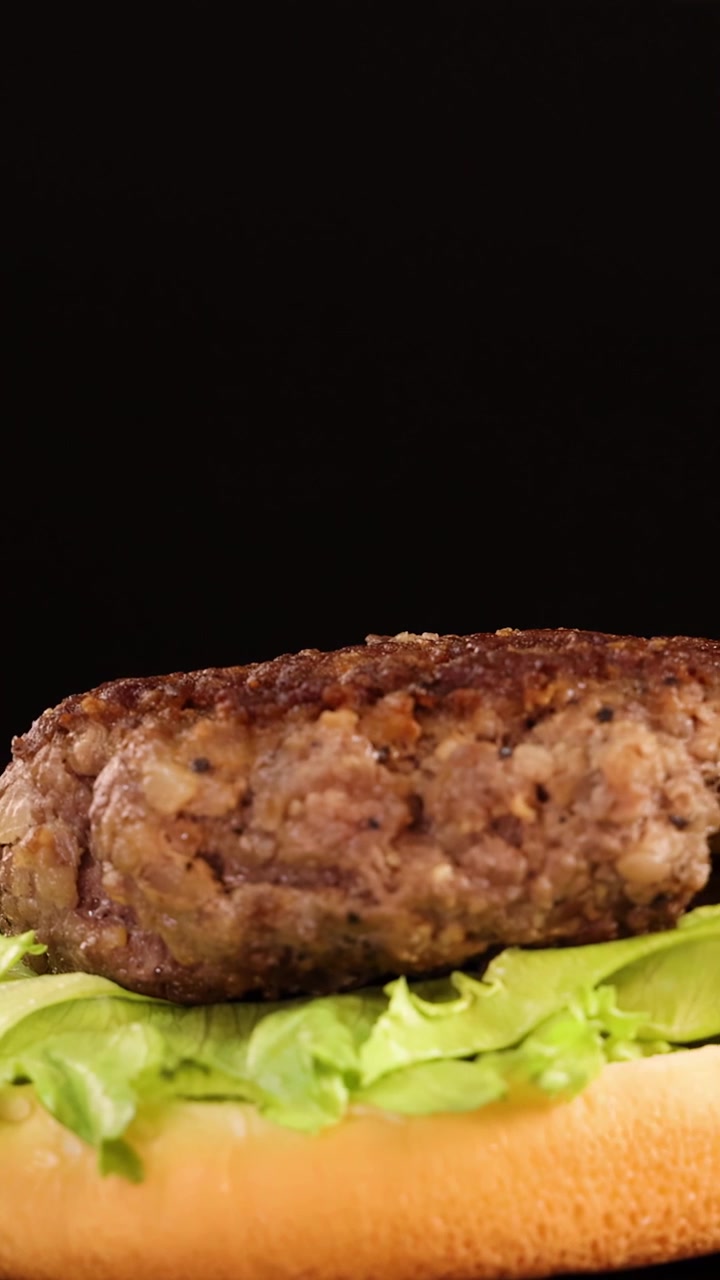 Hand Placing Grilled Beef Patty onto Lettuce on Burger Bun