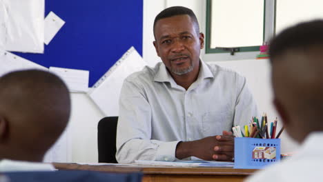 teacher talking from his desk in elementary class, pupil pov