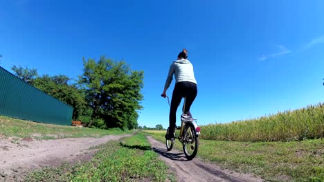 young woman riding vintage bicycle along a rural road in a village