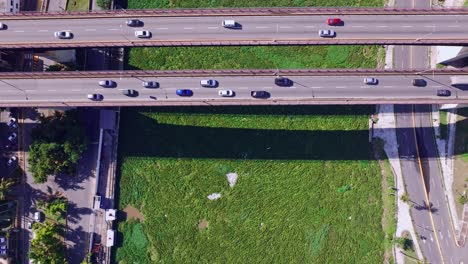 Blick-Von-Oben-Auf-Die-Wasserhyazinthe,-Die-Auf-Dem-Rio-Ozama-Schwimmt,-Mit-Verkehr-Auf-Brücken-In-Der-Dominikanischen-Republik