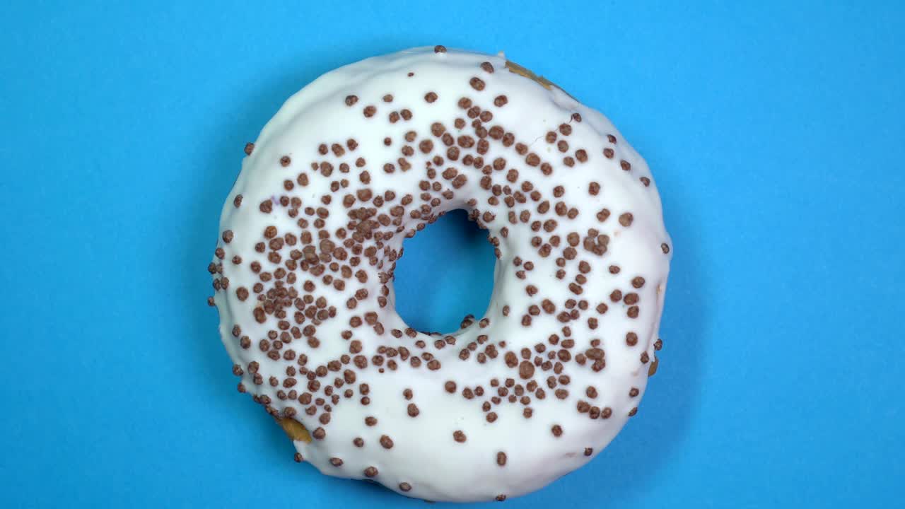 saboroso y fresco rosquilla rosquilla macro disparo de primer plano girando sobre un fondo azul.