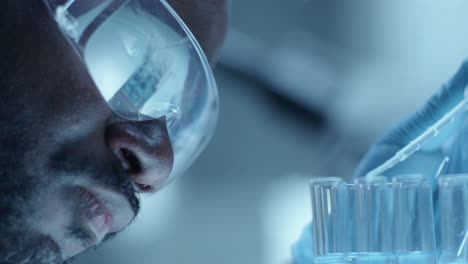 african american chemist dripping liquid in test tubes with pipette in lab