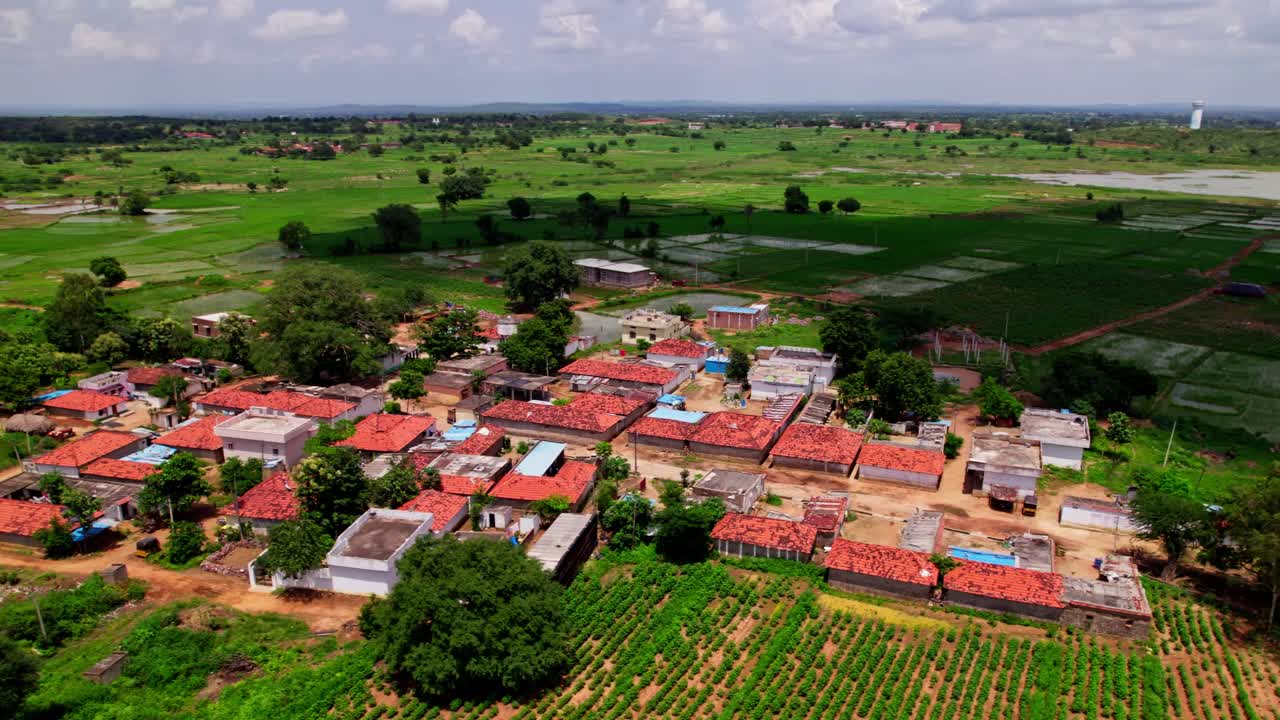 aerial view of small village with lake and shadow of clouds falling on crop fields beautiful scenic location in telangana, india. 4k, semi orbit, drone shot