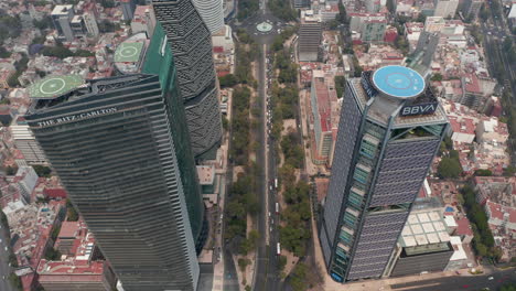 Tilt-down-view-of-multilane-roads-leading-between-downtown-skyscrapers.-Aerial-view-of-tall-buildings-with-helipads-on-roof.-Mexico-City,-Mexico.