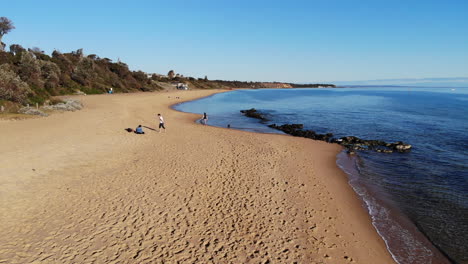 drone flight along the golden sandy beach and blue ocean shoreline of sandringham, melbourne