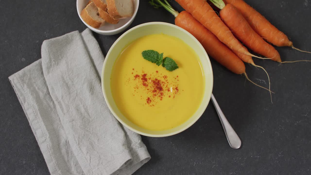 video de sopa de verduras con crema en un cuenco en una mesa gris con zanahorias