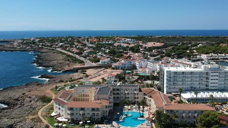 Aerial-shot-of-summer-holiday-hotel-with-swimming-pool-in-Menorca,-Spain