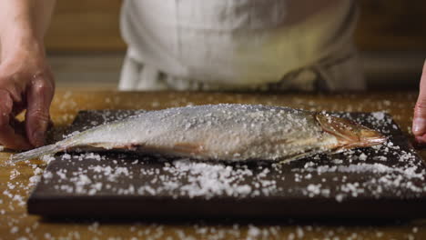 chef throws fat pickled herring into salt pile on board