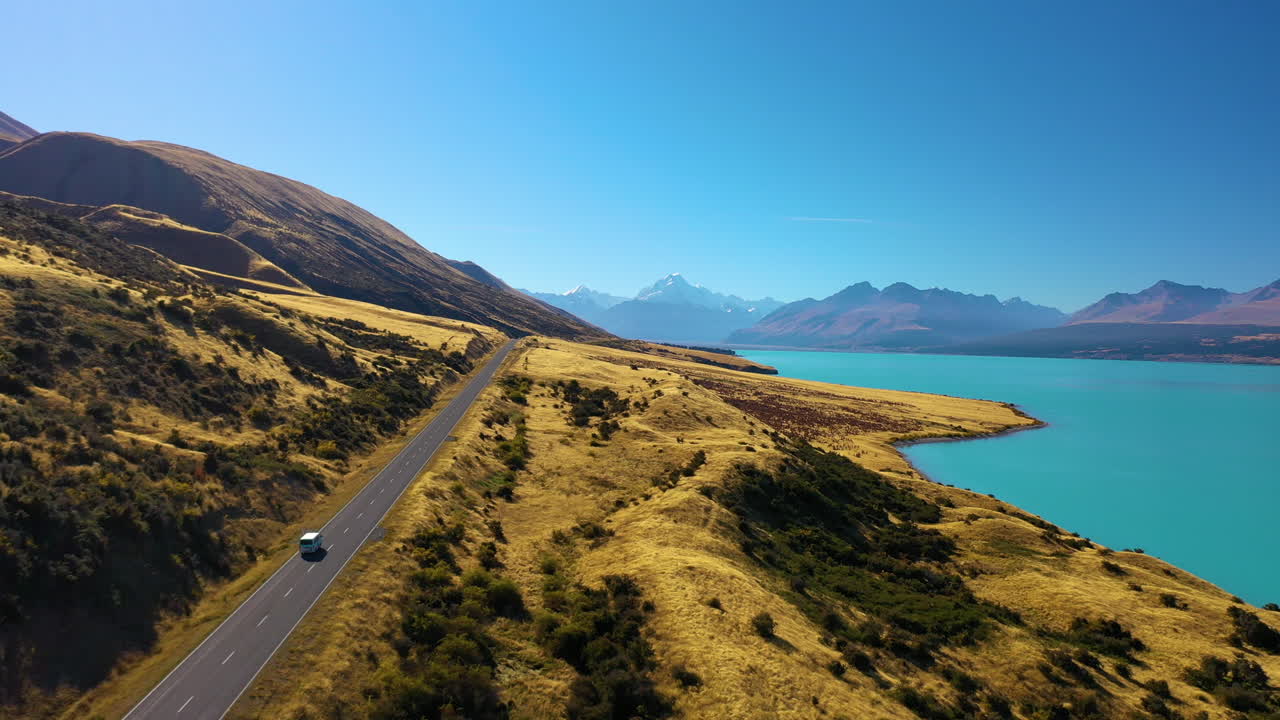 Aerial view of the scenic road along New Zealand's Lake Pukaki with majestic Mount Cook in the distance