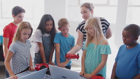 estudiantes con un maestro en una clase de codificación de computadoras después de la escuela aprendiendo a programar un vehículo robot