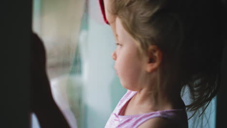 girl-wipes-window-with-rag-helping-mother-to-clean-house