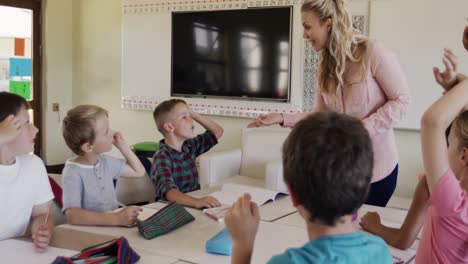 Grupo-De-Niños-Levantando-La-Mano-En-La-Clase