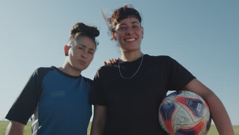 portrait of two female soccer players on green field