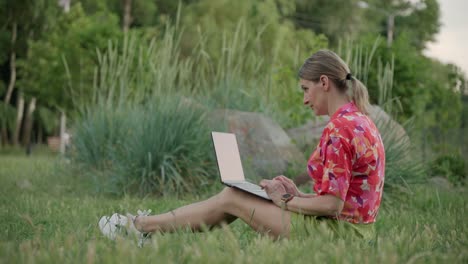 a female freelancer is working on a project using her laptop in a public park.