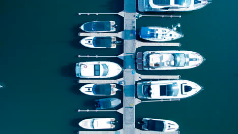 top-down aerial view of boats docked at a marina with clear blue water