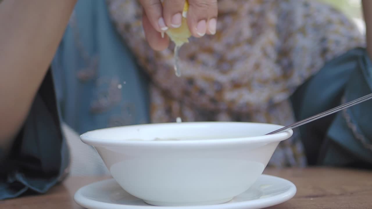 Mujer exprimiendo limón en un tazón de sopa