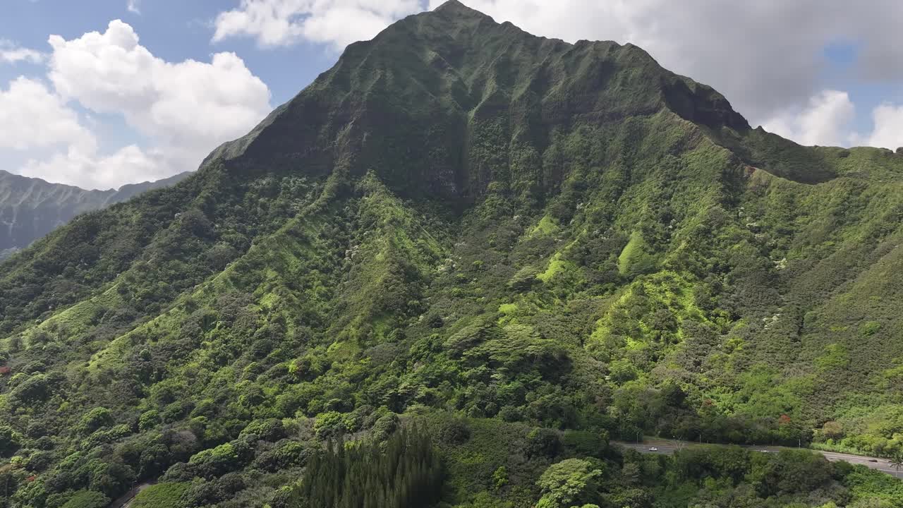 Aerial drone footage over Hawaii’s lush green mountains and tropical coastline, showcasing turquoise ocean waters, palm trees, scenic valleys, and the island’s vibrant natural landscapes from above