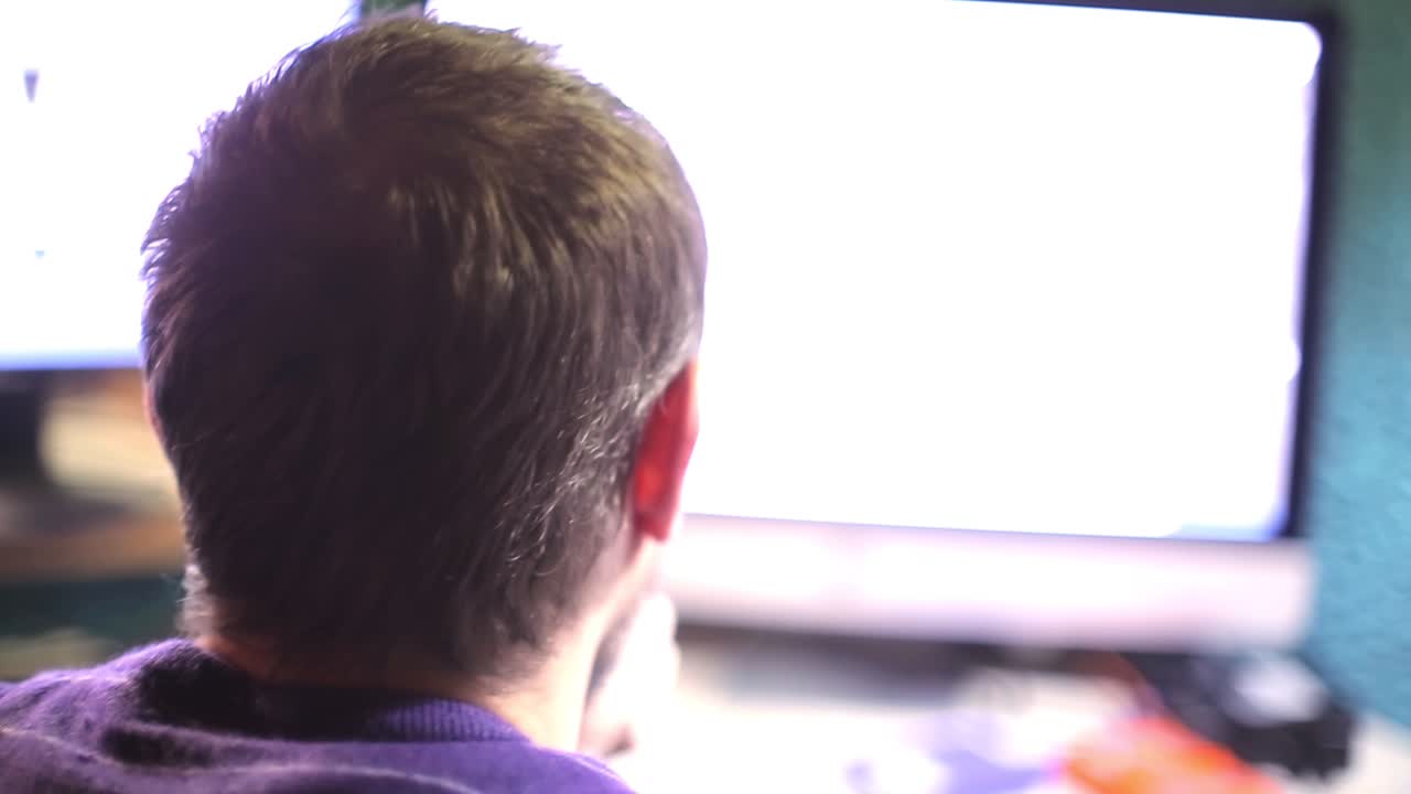 남자는 밝은 컴퓨터 화면을 본다