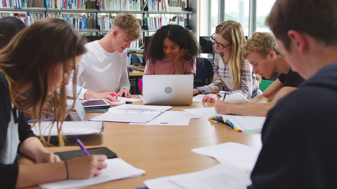 grupo de estudiantes universitarios trabajando en la biblioteca con una computadora portátil