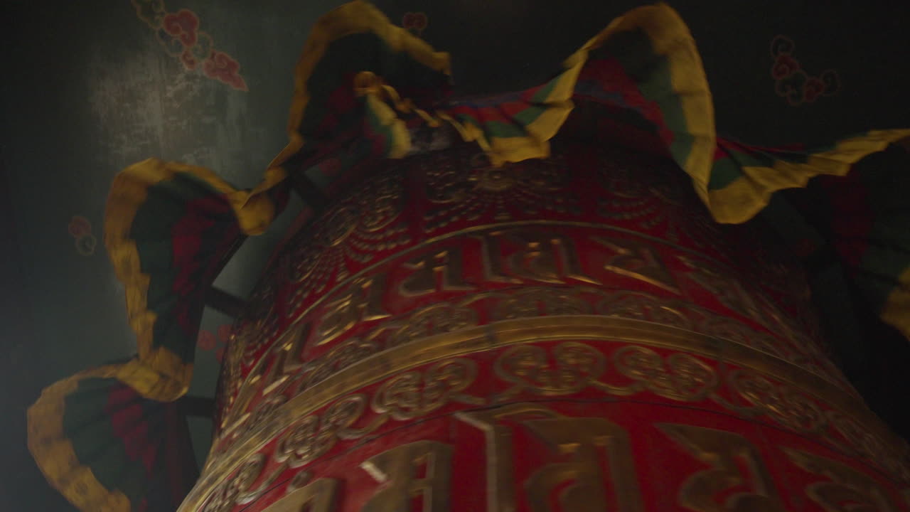 Inside a Buddhist temple in Nepal, a large prayer wheel rotates slowly as devotees and tourists spin it with faith. The motion reflects spiritual belief, mindfulness, and inner peace