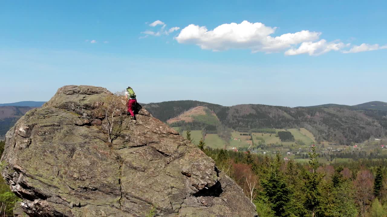 joven exitosa con los brazos levantados en la cima de la montaña.