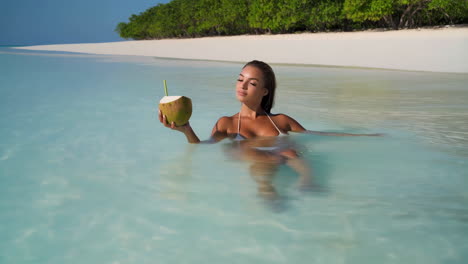 beautiful woman enjoying a coconut drink in tropical ocean