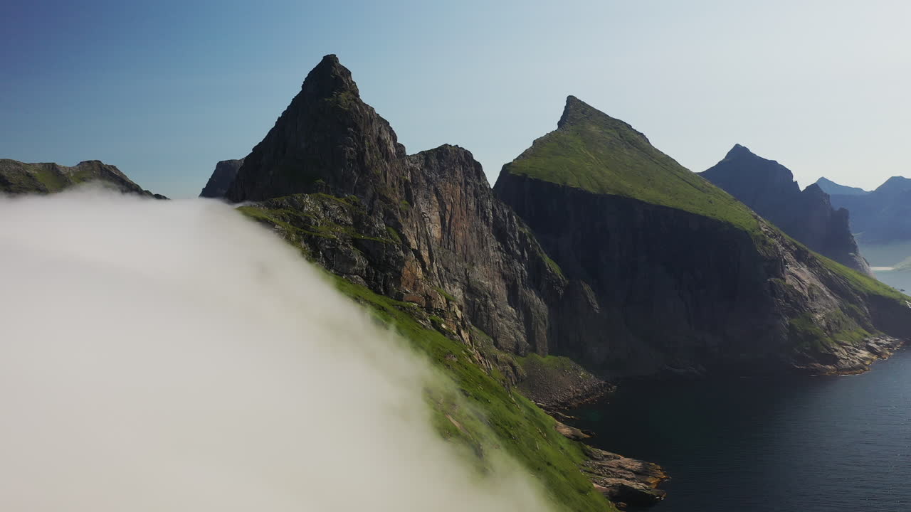 호세이드 해변의 절벽 위로 이동하는 구름의 드론  ⁇ 이 터키즈 파란 물로 드러납니다.