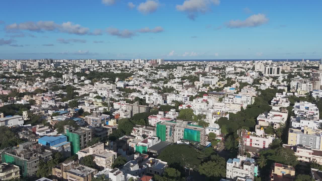 A bird's-eye view of Chennai at sunrise would capture the city's serene beauty, as the first rays of sunlight illuminate its skyline and coastline. T nagar and buildings and houses.
