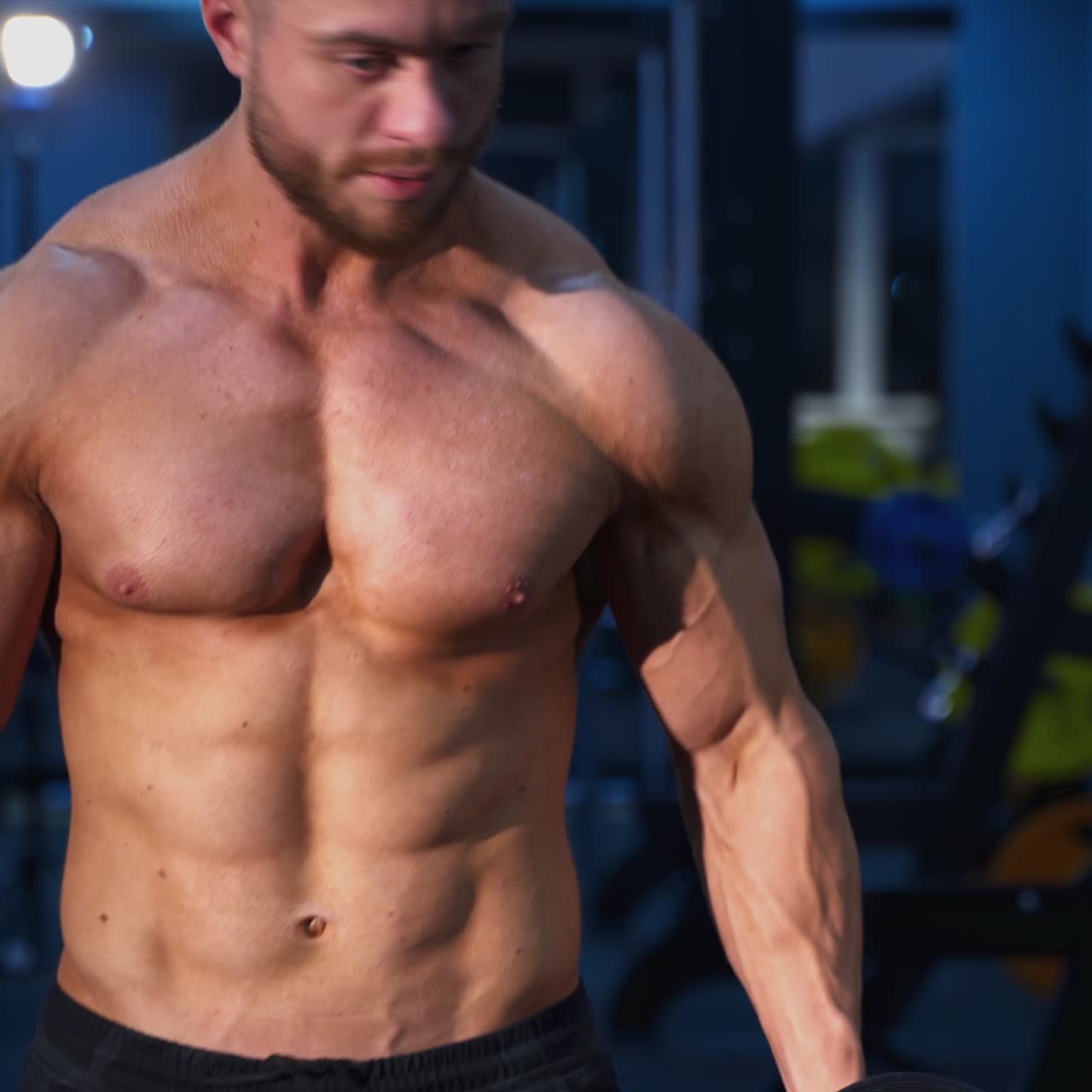 Workout with dumbbells. Sportsman with heavy dumbbells training his arm muscles in the gym. Bodybuilder lifting dumbbells. Healthy lifestyle