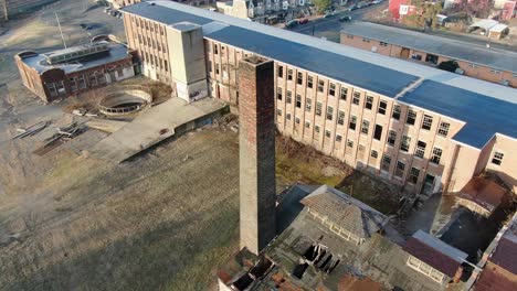 aerial orbiting shot around brick chimney at old closed factory building, site of former silk mill