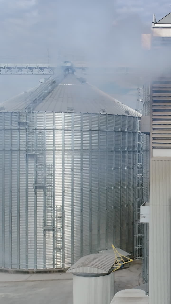 Big factory metal constructions. Huge industrial metal containers. Aerial view. Vertical video