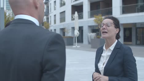 serious businesswoman meeting with partners outside and talking with them