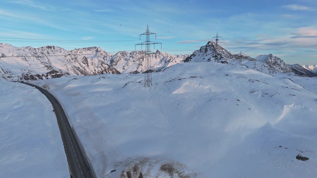 Snowy Bernina Pass with road and mountain peaks under a blue sky