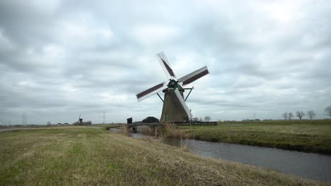 Dutch-windmill-in-wetlands-turning-in-strong-winds,-still-shot